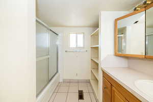 Full bath with vanity, enclosed tub / shower combo, tile patterned floors, and visible vents