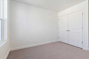 Unfurnished bedroom with baseboards, a closet, and light carpet