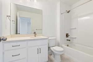 Bathroom featuring toilet, shower / washtub combination, tile patterned flooring, and vanity