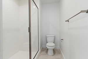 Full bathroom with toilet, baseboards, a shower stall, and tile patterned flooring