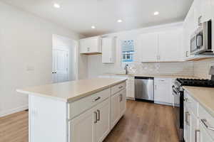 Kitchen with appliances with stainless steel finishes, a sink, light wood-style flooring, and tasteful backsplash