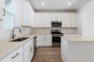 Kitchen with a sink, light countertops, white cabinets, and stainless steel appliances