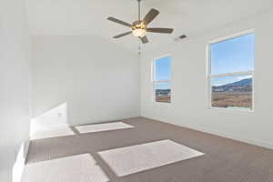 Spare room with visible vents, carpet floors, baseboards, a ceiling fan, and vaulted ceiling