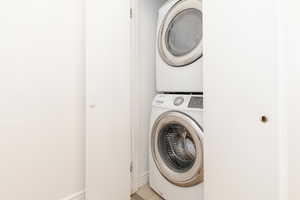 Washroom featuring stacked washer / dryer, laundry area, and baseboards