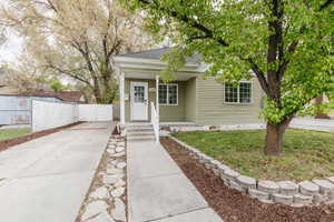 View of front of property with concrete driveway, roof with shingles, covered porch, fence, and a front lawn