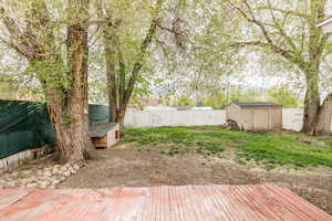 View of yard with an outdoor structure, a storage shed, a wooden deck, and a fenced backyard