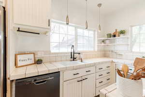 Kitchen with a sink, open shelves, tasteful backsplash, dishwashing machine, and decorative light fixtures