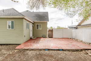 Back of property with a deck, a gate, a fenced backyard, and a shingled roof