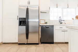 Kitchen featuring light tile patterned floors, dishwashing machine, stainless steel refrigerator with ice dispenser, and tile countertops