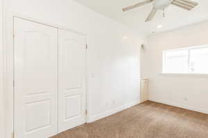 Unfurnished bedroom featuring arched walkways, a closet, ceiling fan, carpet flooring, and baseboards