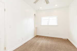Unfurnished room with light colored carpet, ceiling fan, arched walkways, and baseboards