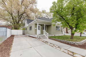 Bungalow-style home with driveway, fence, and a shingled roof