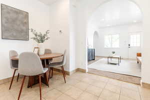Dining area featuring baseboards, light tile patterned floors, arched walkways, and recessed lighting