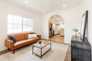 Living room with recessed lighting, baseboards, light carpet, and arched walkways