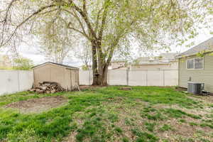View of yard featuring a storage shed, cooling unit, an outbuilding, and a fenced backyard