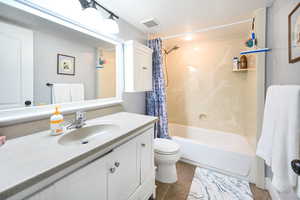Full bath featuring toilet, visible vents, shower / bath combo with shower curtain, and vanity
