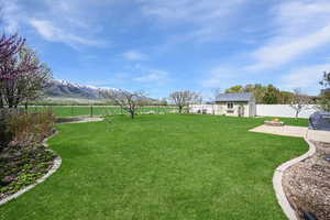 View of yard featuring an outdoor fire pit, a fenced backyard, a mountain view, a patio area, and an outdoor structure