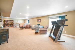 Carpeted living area with recessed lighting, baseboards, visible vents, and a wood stove