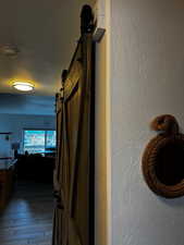 Corridor featuring a barn door, hardwood / wood-style flooring, a textured ceiling, and a textured wall