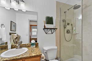 Full bathroom with a tile shower, toilet, and vanity