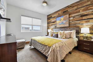 Bedroom with wooden walls, carpet flooring, and ceiling fan