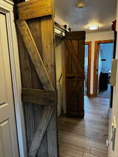 Corridor featuring a textured ceiling, a barn door, and hardwood / wood-style flooring