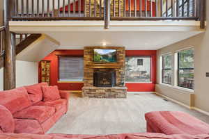 Carpeted living room with a large fireplace, baseboards, visible vents, and a high ceiling