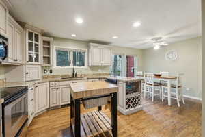 Kitchen with open shelves, a sink, stainless steel appliances, a ceiling fan, and a peninsula
