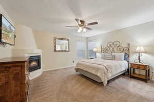 Bedroom with carpet floors, a ceiling fan, baseboards, and a fireplace