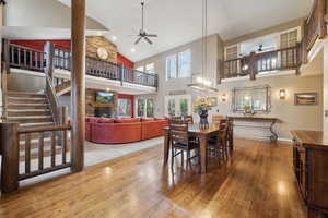 Dining room featuring baseboards, a ceiling fan, high vaulted ceiling, and wood finished floors