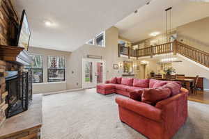 Living area with a towering ceiling, a fireplace, stairway, carpet floors, and baseboards