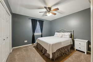 Bedroom with a closet, a ceiling fan, baseboards, and carpet floors