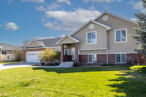 Tri-level home with stucco siding, a front yard, driveway, and brick siding