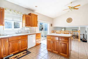 Kitchen with white dishwasher, light countertops, ceiling fan, and a sink