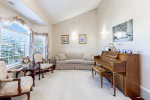 Living room featuring vaulted ceiling, light carpet, and visible vents
