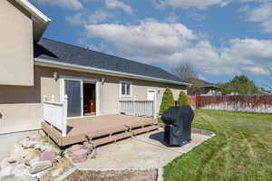 Back of house with fence, roof with shingles, a wooden deck, stucco siding, and a yard