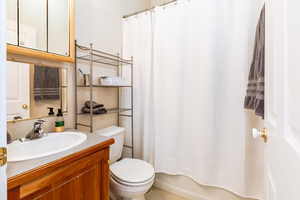 Full bath with vanity, shower / bathtub combination with curtain, and toilet
