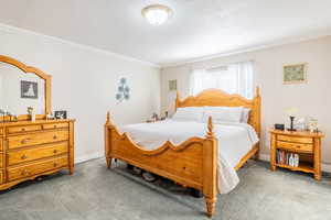 Carpeted bedroom with baseboards and ornamental molding