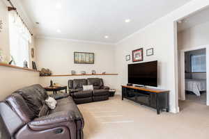 Living room featuring baseboards, ornamental molding, recessed lighting, and light carpet