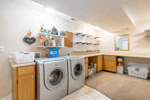 Washroom featuring separate washer and dryer, cabinet space, light tile patterned floors, and visible vents
