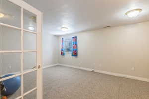Empty room with visible vents, carpet, a textured ceiling, and baseboards