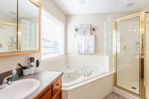 Bathroom featuring a whirlpool tub, a stall shower, and vanity