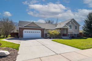 Tri-level home with a garage, fence, a front yard, brick siding, and concrete driveway