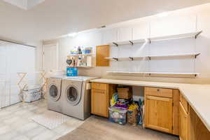 Laundry room featuring separate washer and dryer, cabinet space, light tile patterned flooring, and visible vents