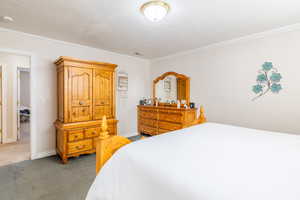 Bedroom featuring baseboards, ornamental molding, and carpet