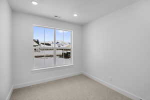 Empty room with visible vents, carpet, baseboards, and recessed lighting