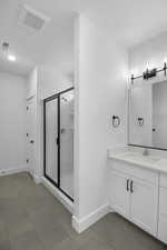 Bathroom featuring vanity, tile patterned floors, baseboards, visible vents, and a stall shower