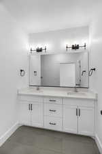 Full bathroom featuring double vanity, baseboards, a sink, and tile patterned flooring