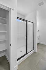 Bathroom with baseboards, tile patterned flooring, a stall shower, and visible vents