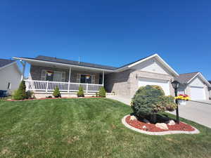 Single story home with covered porch, brick siding, a front yard, and a garage